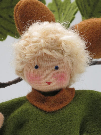 Porträt des Eichel-Jungen mit blondem Haar und grünem Filzmantel als handgemachtes Waldorf-Blumenkind.