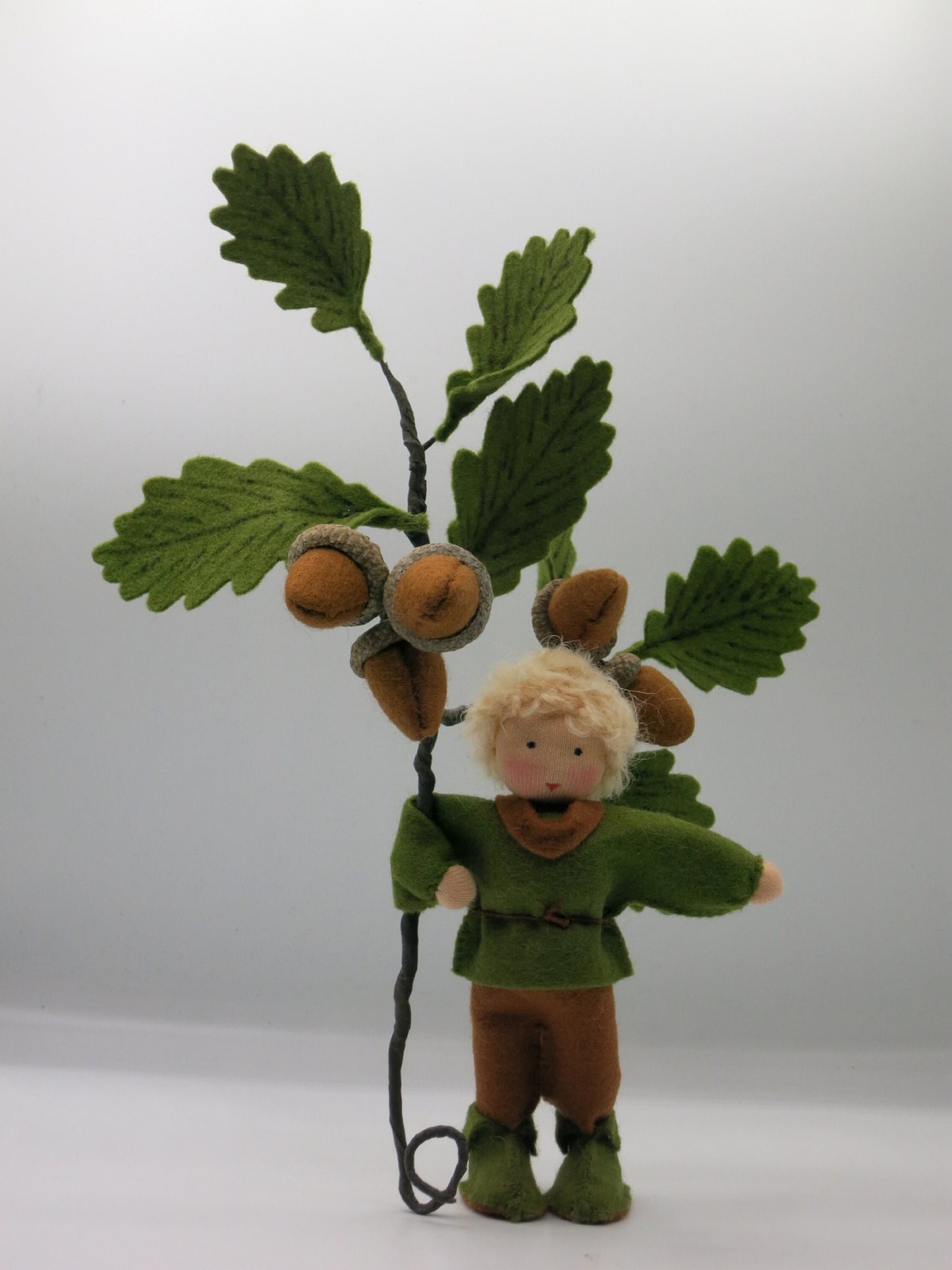 Handgefertigter Eichel-Junge als Filzpuppe mit großem Eichenzweig und Eicheln für die Waldorf-Herbstdekoration.