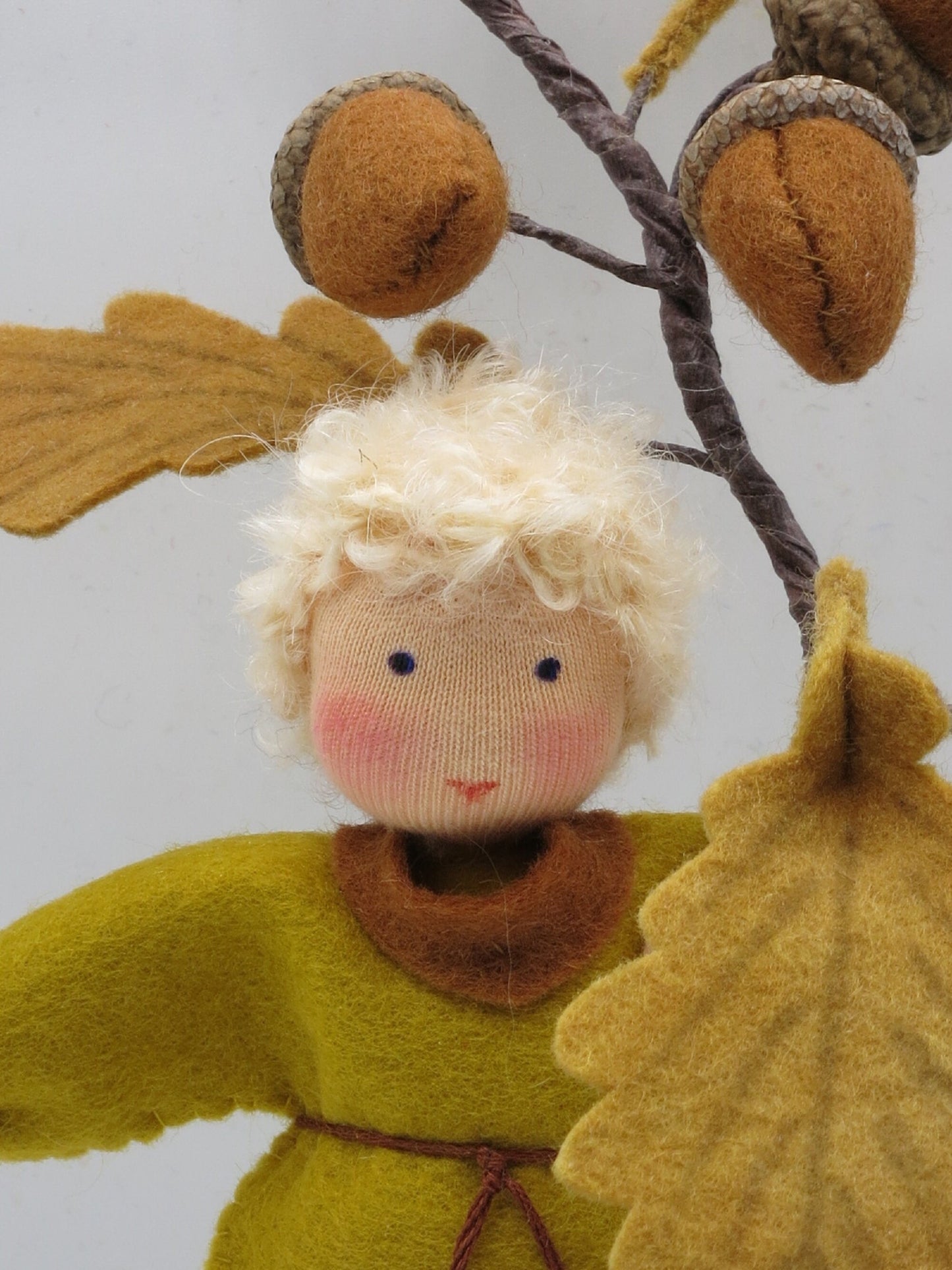 Herbstporträt des handgefertigten Eichel-Jungen mit Filzeicheln und Eichenlaub für den Waldorf-Jahreszeitentisch