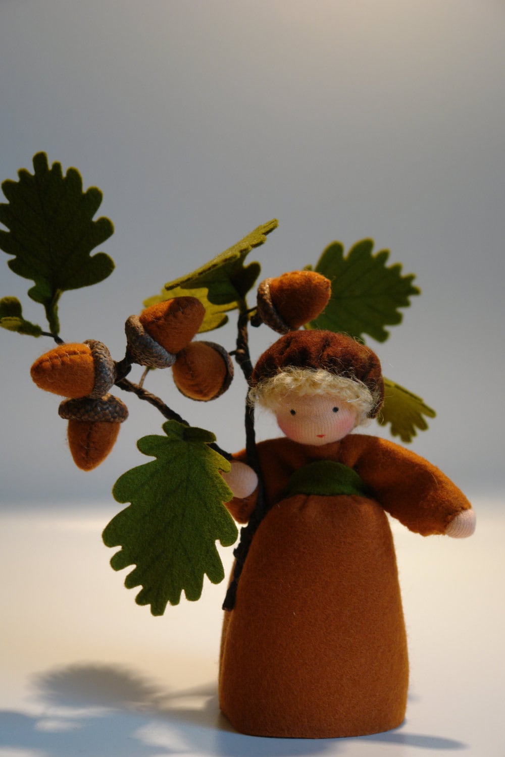Handgefertigtes Eichel-Kind mit blondem Haar, braunem Filzkleid, Eicheln und Eichenlaub für den Waldorf-Herbsttisch