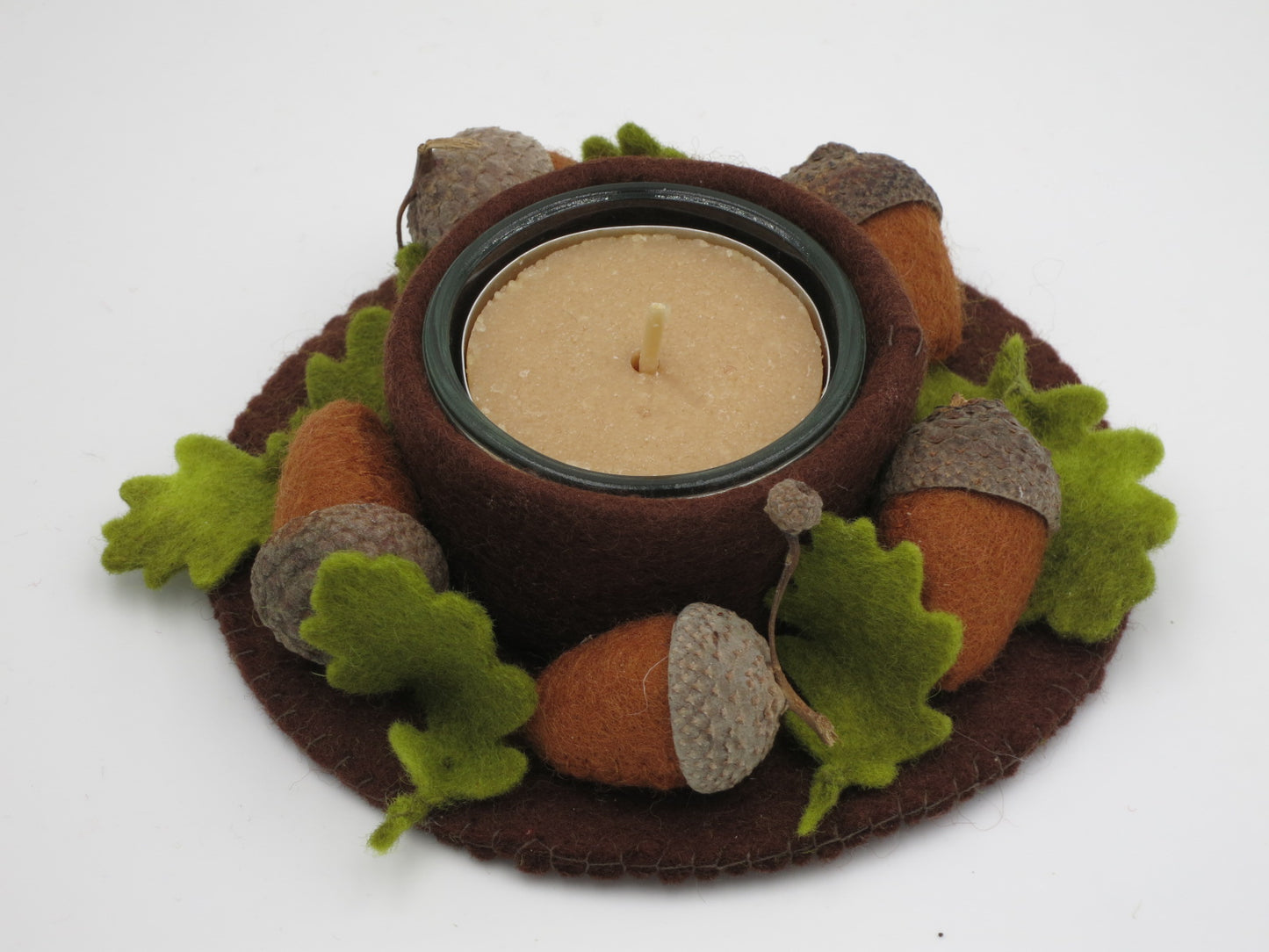Eichel-Licht aus Filz mit Teelicht, Eicheln und grünen Blättern in Draufsicht als Waldorf-Herbstdeko.