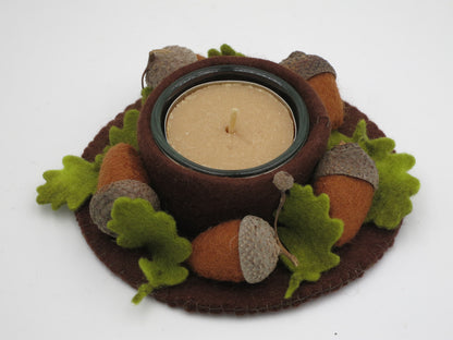 Eichel-Licht aus Filz mit Teelicht, Eicheln und grünen Blättern in Draufsicht als Waldorf-Herbstdeko.