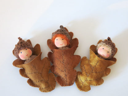 Drei handgefertigte Eichelbabys als Filzpuppen in Blätterhüllen für den herbstlichen Waldorf-Jahreszeitentisch.