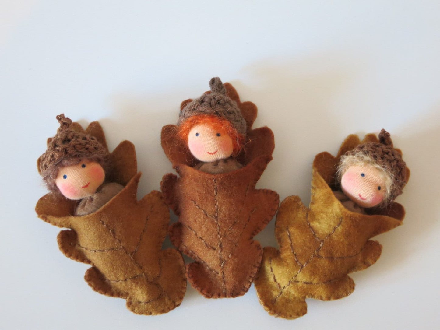 Drei Eichelbabys als handgefertigte Blätterkinder aus Filz für die herbstliche Waldorf-Dekoration.