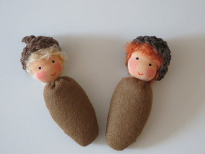 Zwei handgefertigte Eichelbabys aus Filz mit blondem und rotem Haar als Waldorf-Herbstdekoration.