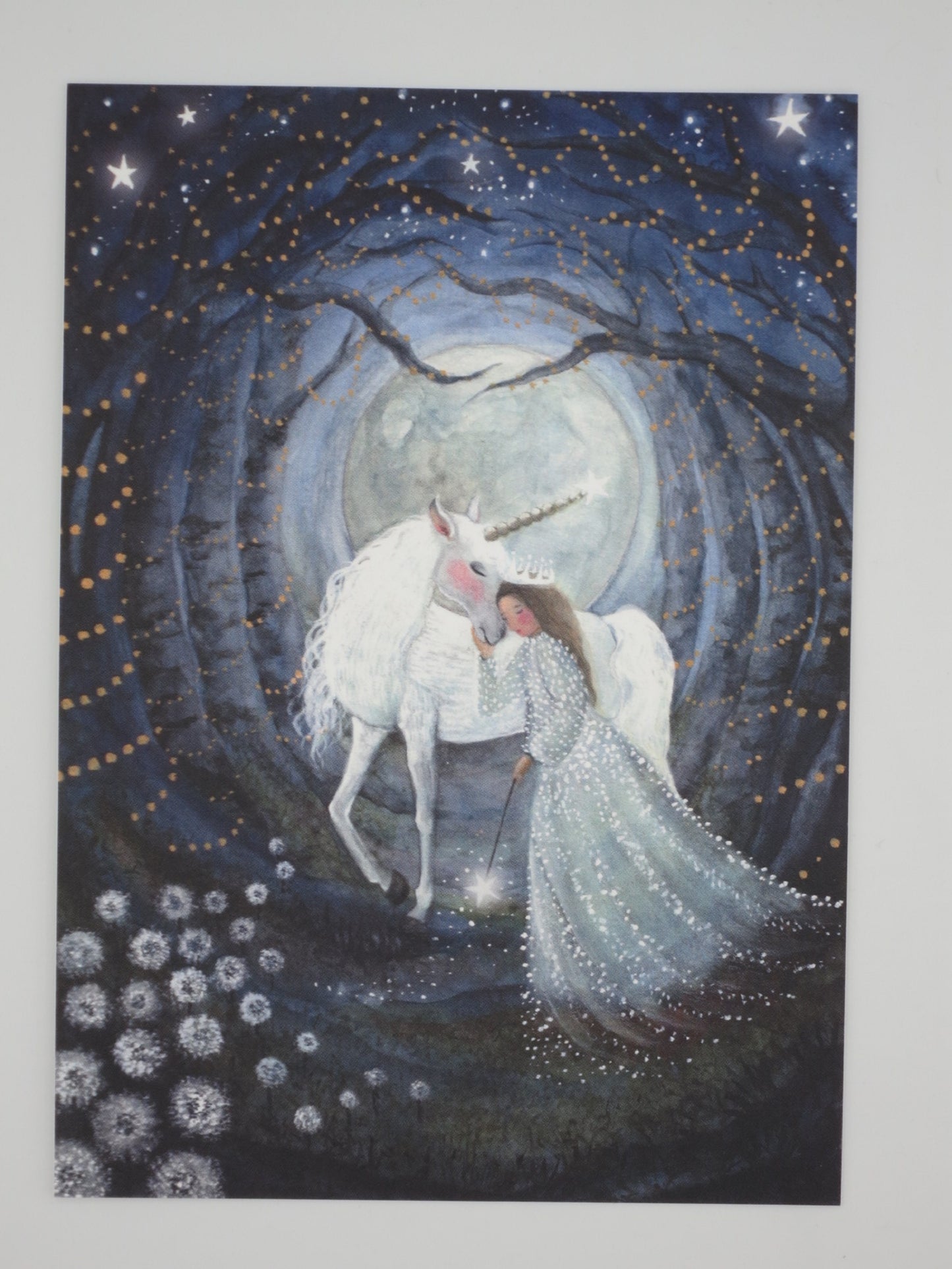 Einhorn-Postkarte für Kinder: Mädchen umarmt Einhorn mit Zauberstab vor Vollmond im Sternenwald