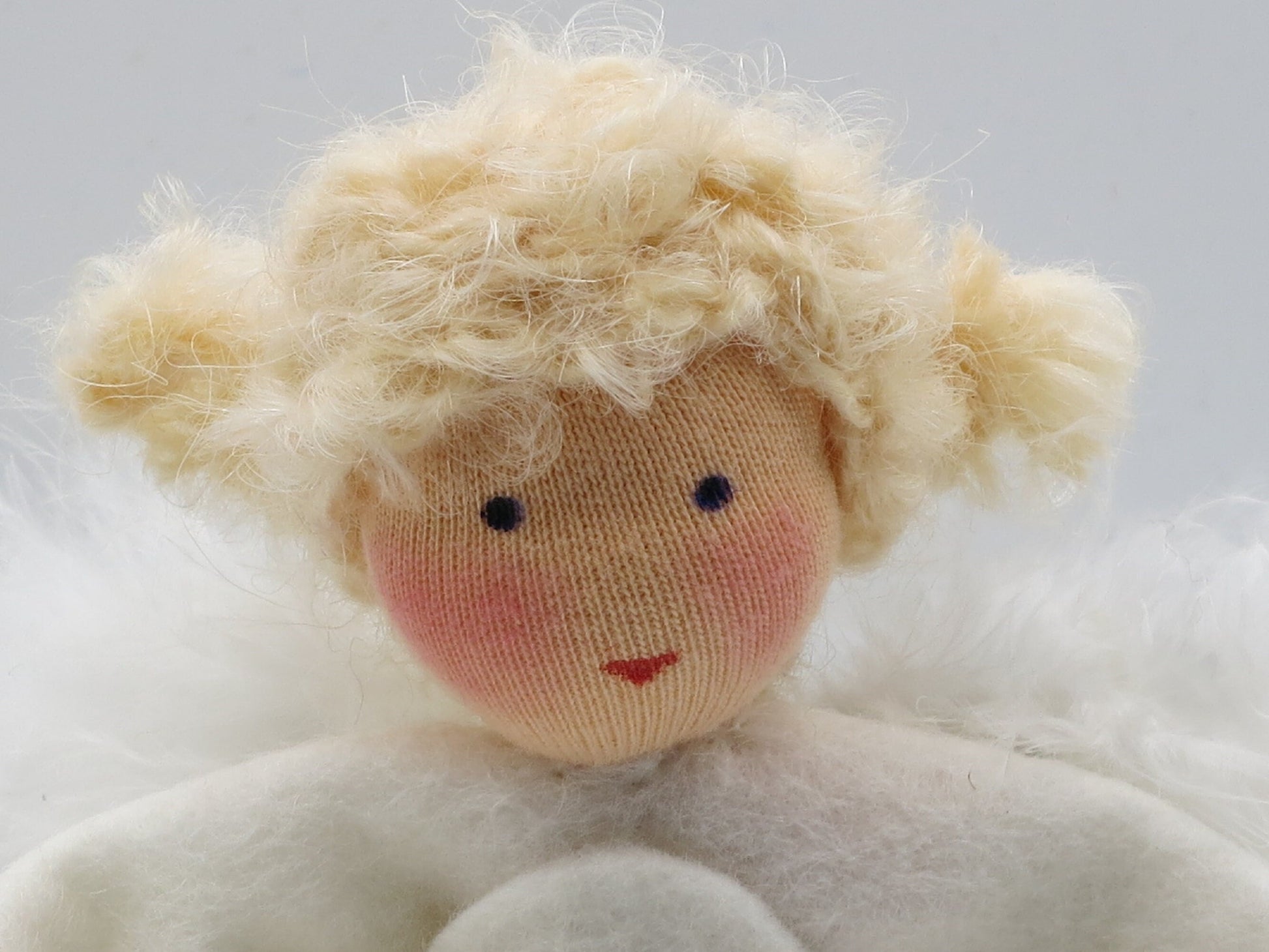 Detailaufnahme des blonden Engels aus Wollfilz mit weißen Flügeln für die Weihnachtsdekoration.