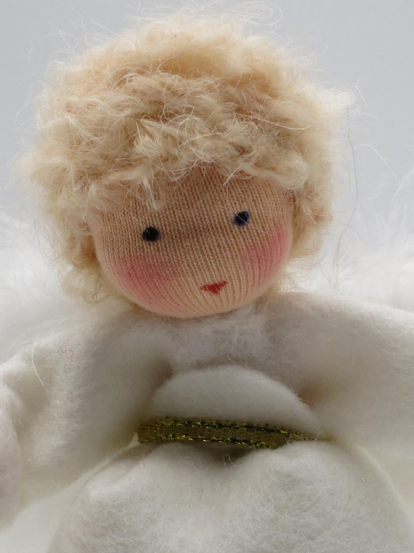 Porträt eines handgefertigten Engels aus Wollfilz mit weißen Flügeln für die Waldorf-Weihnachtsdekoration.