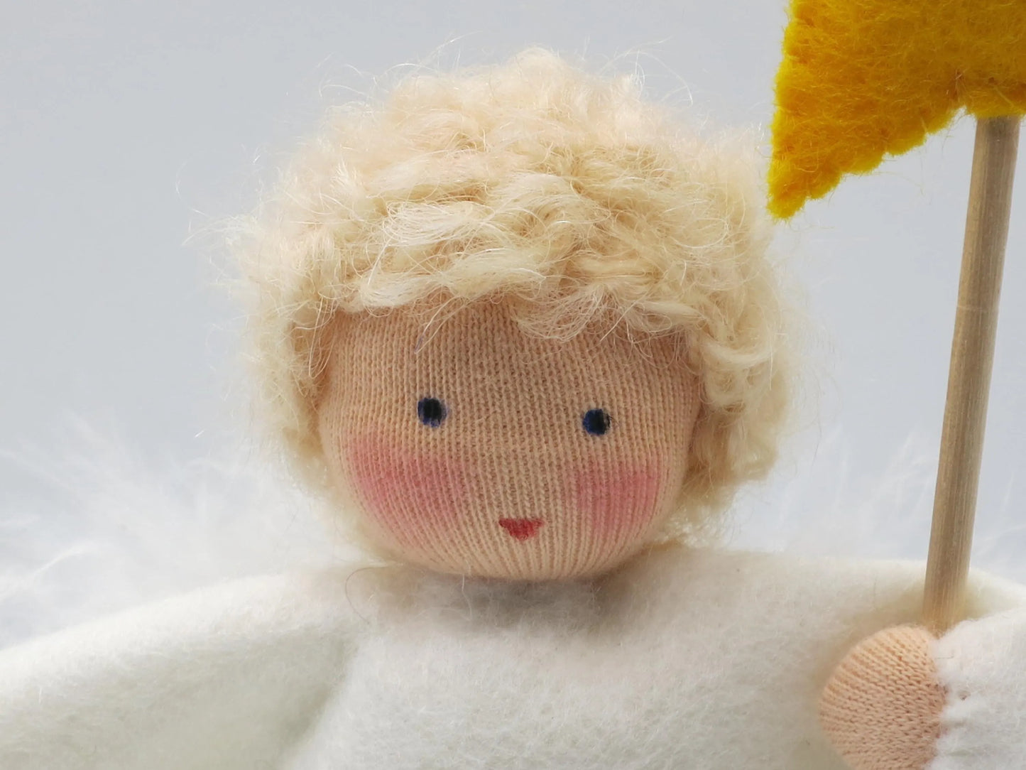 Detailaufnahme des Engel-Jungen aus Wollfilz mit blondem Haar und goldenem Sternstab für die Weihnachtszeit.