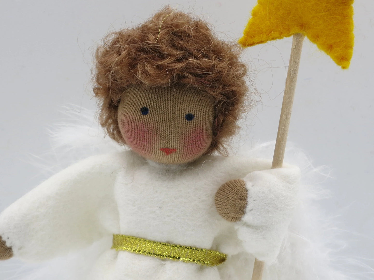 Detailaufnahme des Engel-Jungen aus Wollfilz mit braunem Haar, weißen Flügeln und Sternstab.