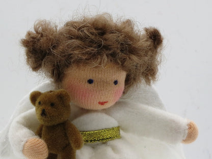 Detailansicht des handgefertigten Wollfilz-Engelchens mit braunem Lockenhaar, Teddy und weißen Flügeln.