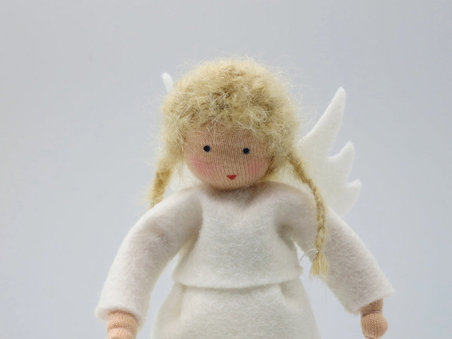 Porträt des handgefertigten Engelchens aus Wollfilz mit blondem Haar, weißem Kleid und kleinen Flügeln.