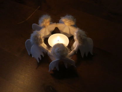 Engelchenkreis aus Wollfilz um ein leuchtendes Teelicht als stimmungsvolle Adventsdekoration auf dem Jahreszeitentisch.
