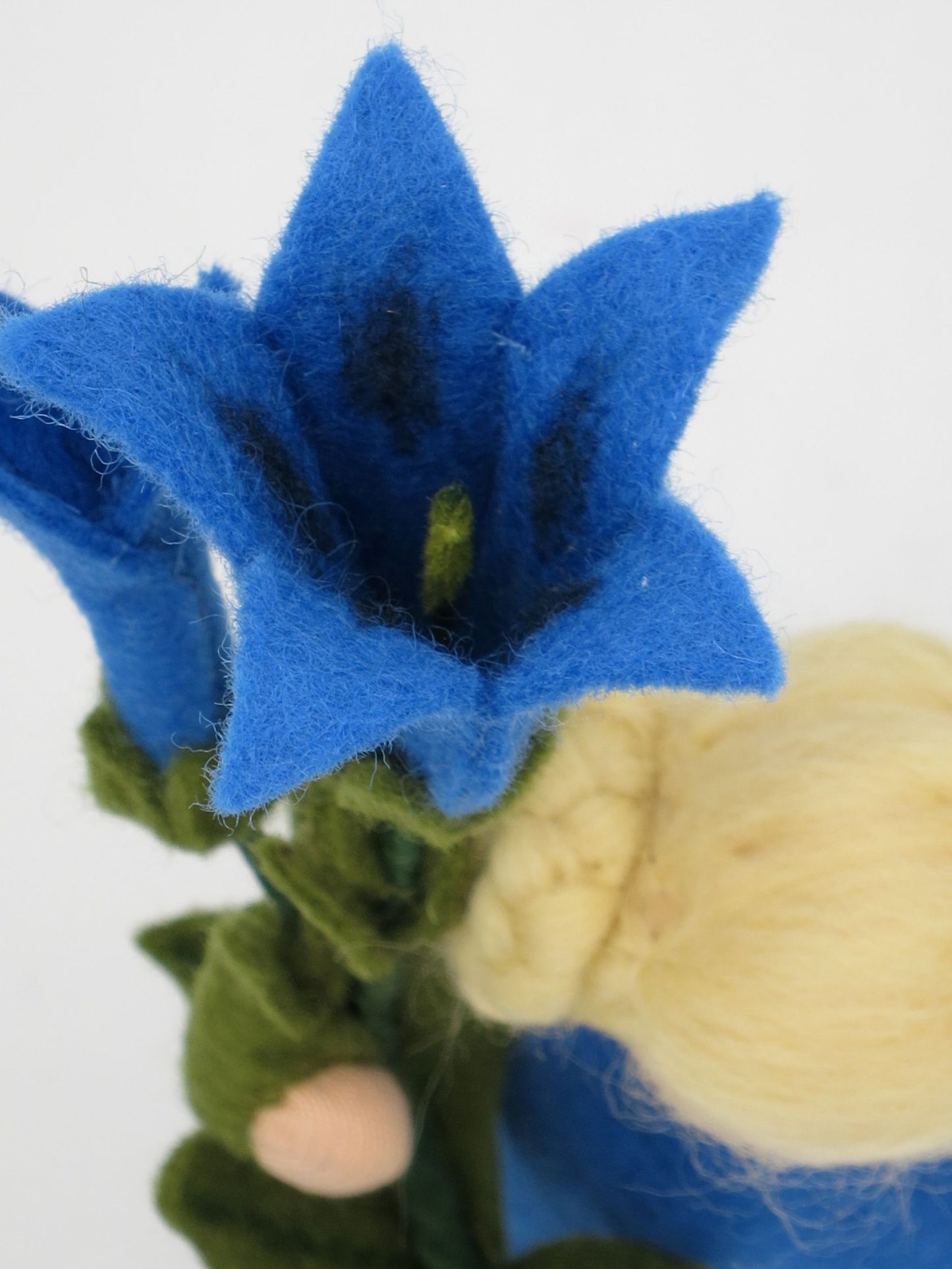 Detailansicht der blauen Enzianblüte aus Wollfilz am handgefertigten Sommer-Blumenkind.