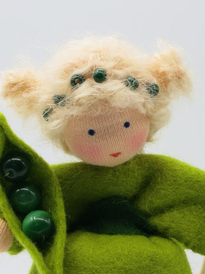 Detailansicht des Erbsen-Früchtekinds aus Wollfilz mit grüner Schote, Erbsen und blondem Haar.