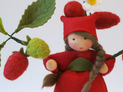 Frontalansicht des handgefertigten Erdbeer-Blumenkinds aus Wollfilz mit roten und grünen Erdbeeren am Zweig.