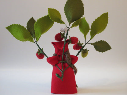 Rückansicht des handgefertigten Erdbeer-Blumenkinds aus Wollfilz mit rotem Kleid, Zöpfen und Erdbeerzweig.