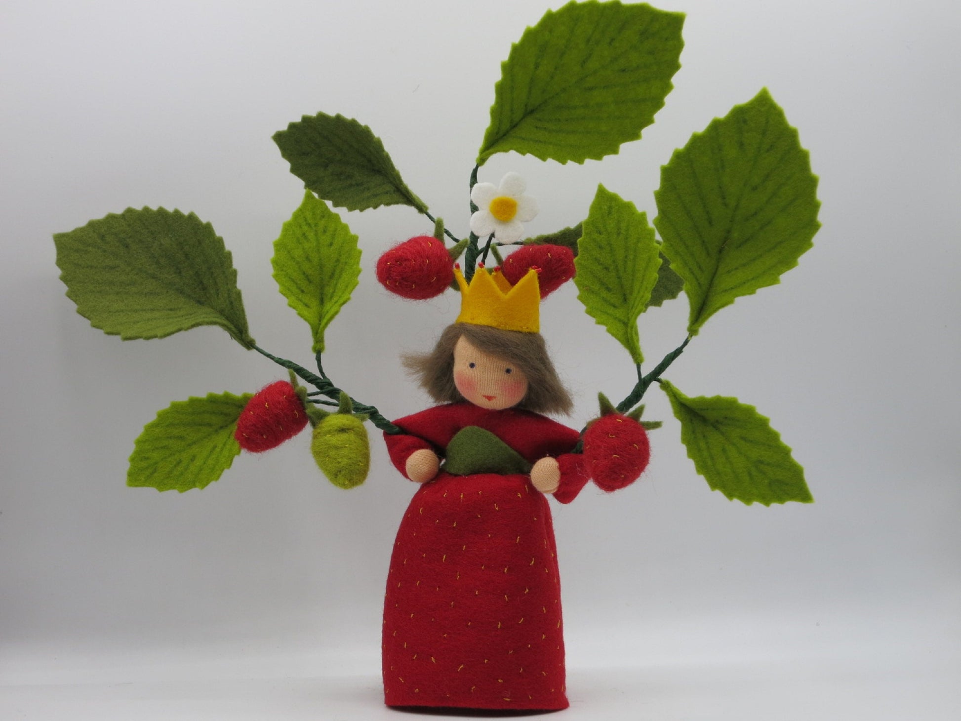 Handgefertigte Erdbeerprinzessin aus Wollfilz mit Erdbeerzweig, grünen Blättern und gelber Krone als Jahreszeitentisch-Dekoration.