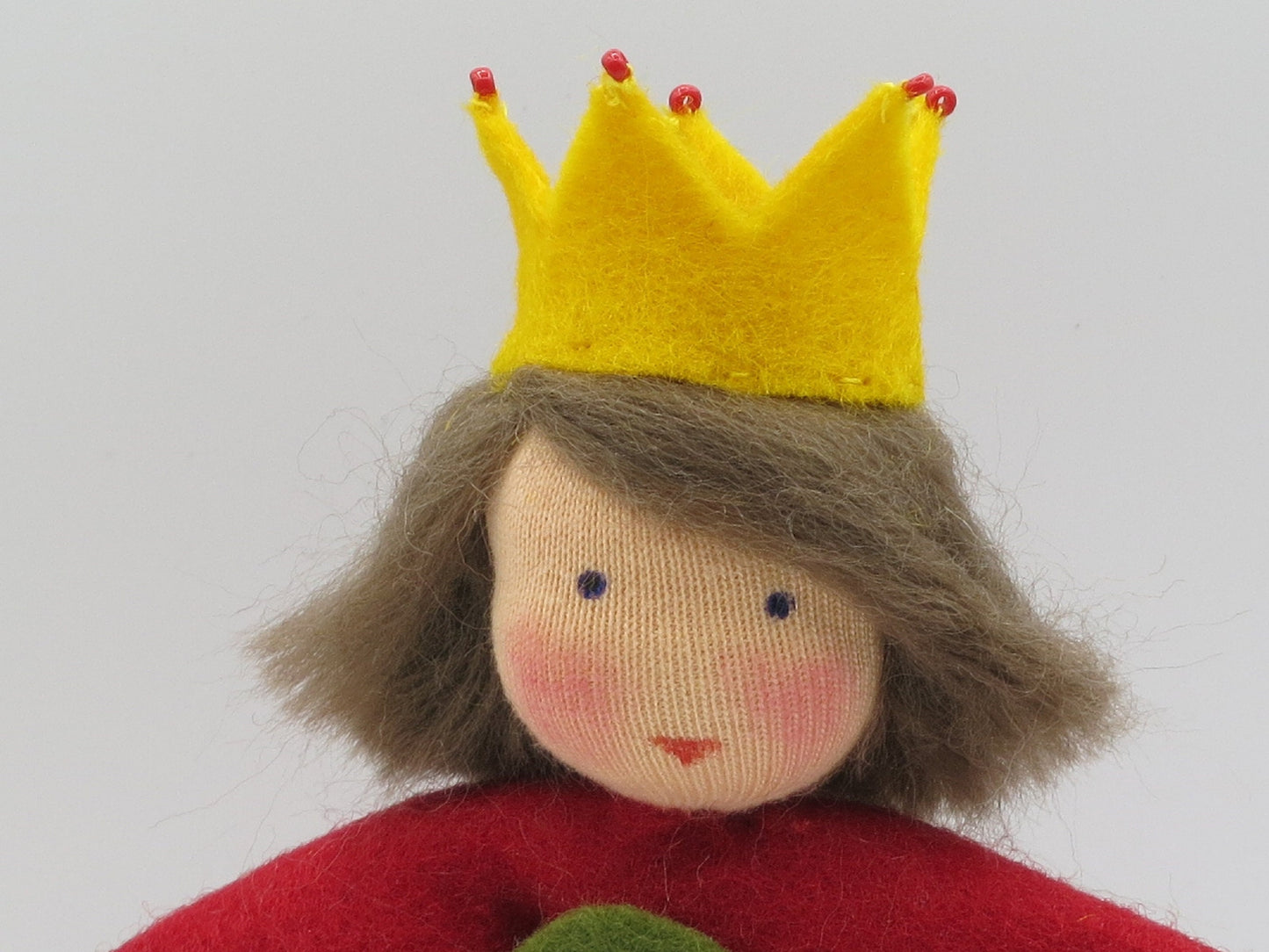 Nahaufnahme der Erdbeerprinzessin aus Wollfilz mit gelber Krone und braunem Haar als Sommer-Blumenkind.