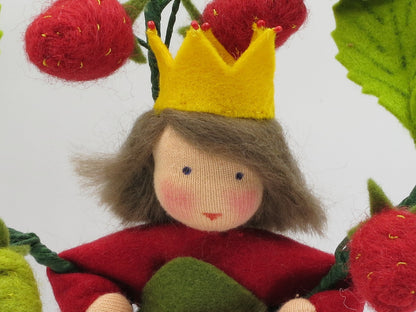 Porträt der handgefertigten Erdbeerprinzessin aus Wollfilz mit gelber Krone, braunem Haar und roten Erdbeeren.