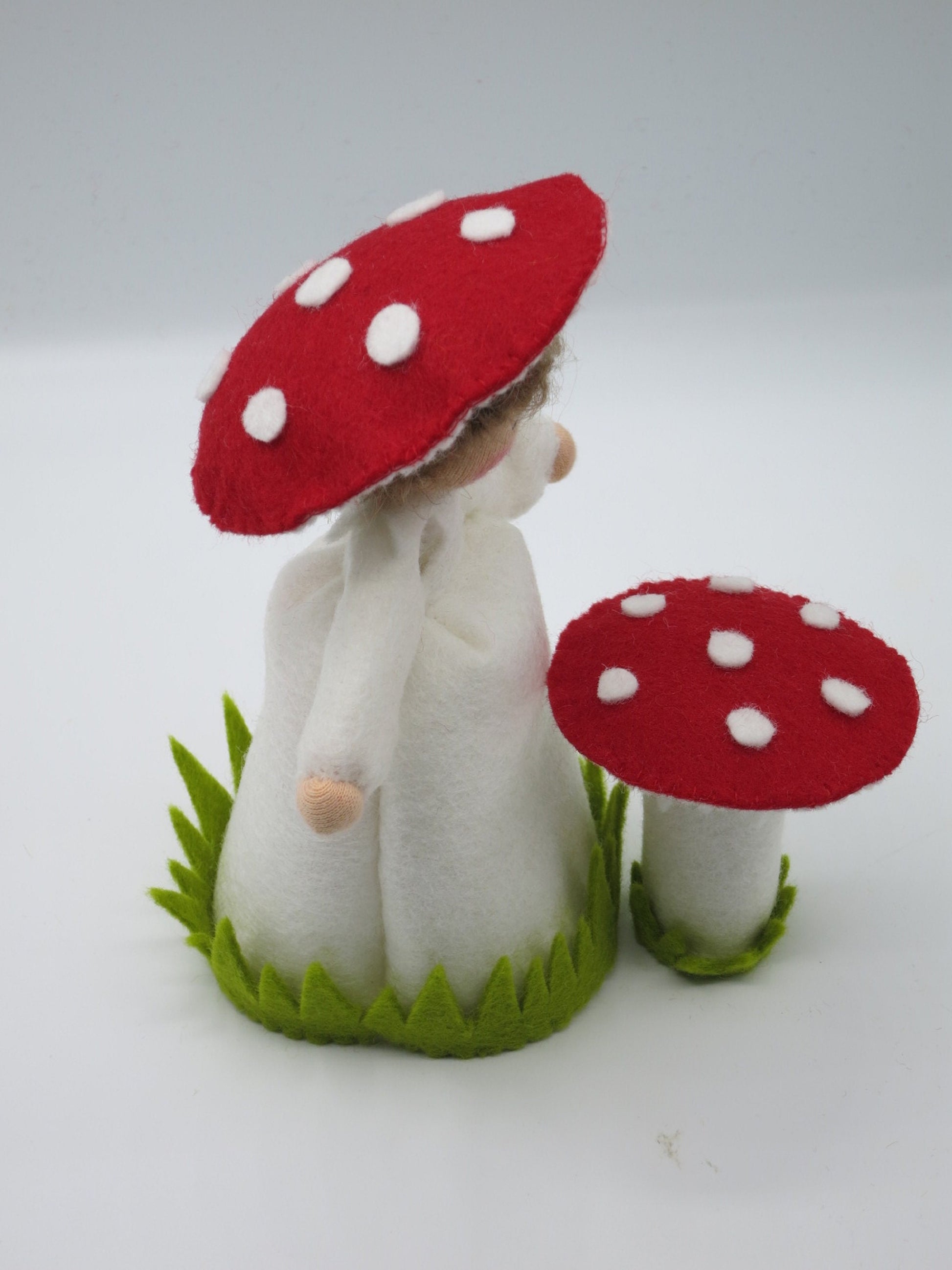 Ansicht des Fliegenpilz-Blumenkinds aus Wollfilz mit rot-weißem Pilzhut und kleinem Fliegenpilz als Herbstdekoration.