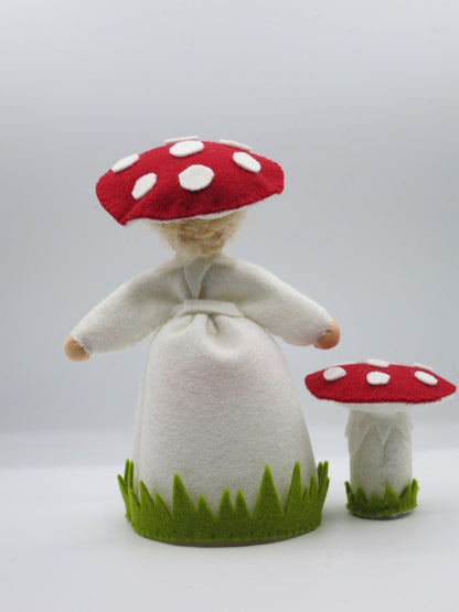 Rückansicht des Fliegenpilz-Blumenkinds aus Wollfilz mit rot-weißem Pilzhut, weißem Gewand und kleinem Fliegenpilz.