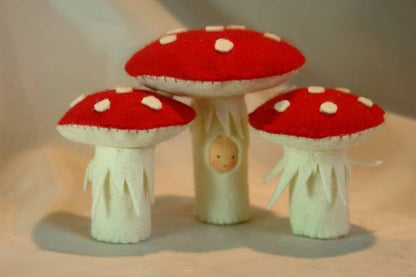 Drei handgefertigte Fliegenpilze aus Wollfilz mit roten Hüten und weißen Punkten als Herbstdekoration für den Jahreszeitentisch.