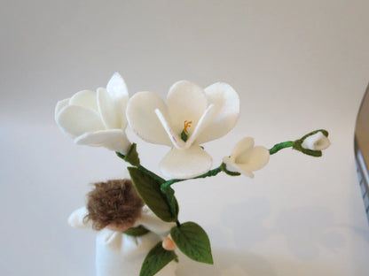 Detailansicht der weißen Freesienblüten und grünen Blätter am handgefertigten Freesien-Blumenkind aus Wollfilz.