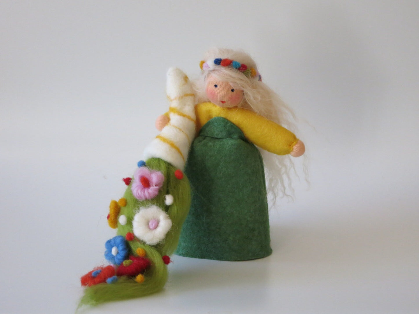 Frühlingsfigur frontal mit grünem Filzkleid, gelben Ärmeln, Blumenkranz und farbenfroher Blumenwiese