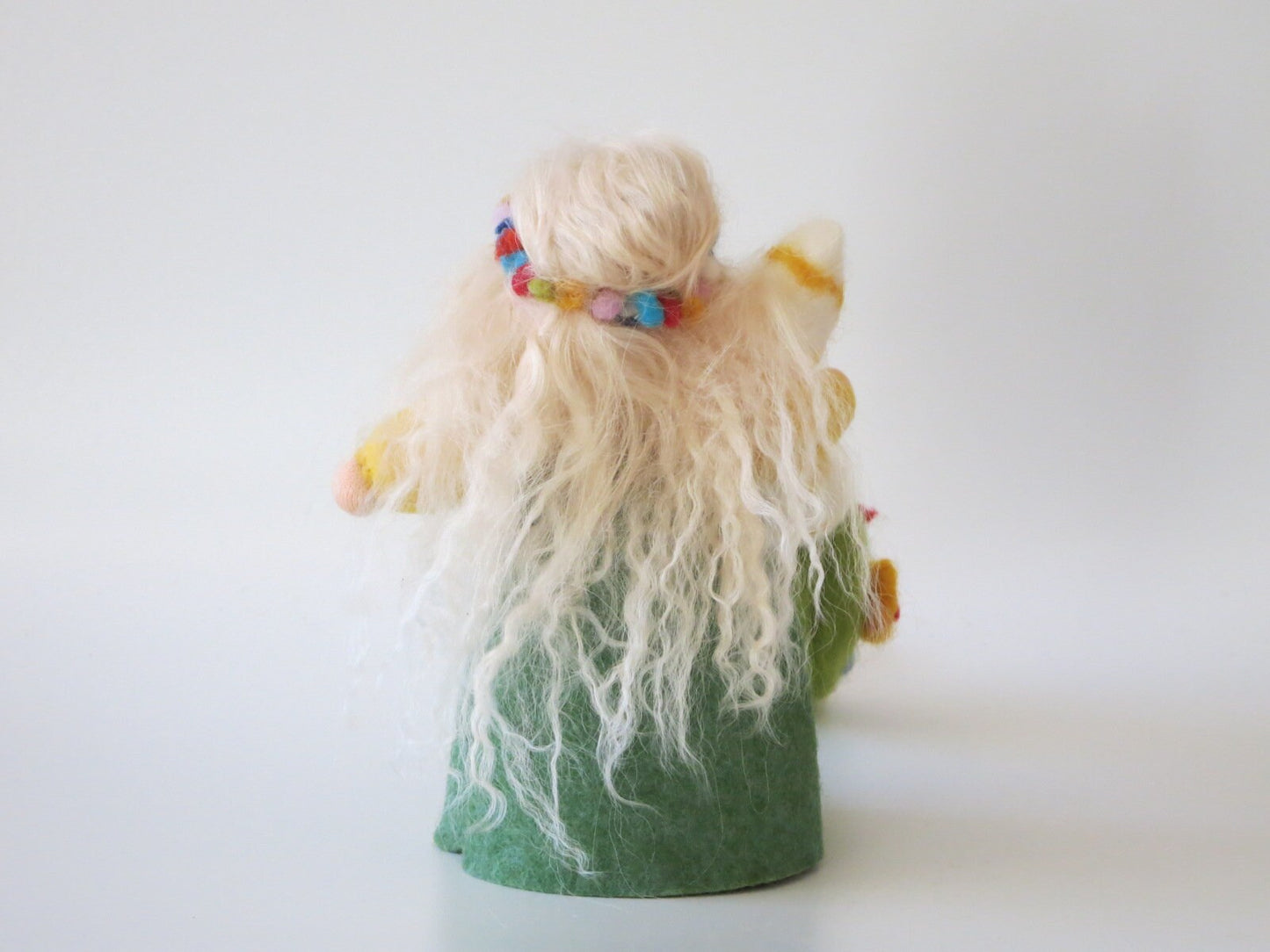 Rückansicht der Frühlingsfigur mit langem blondem Wollhaar, buntem Blumenkranz und grünem Filzkleid