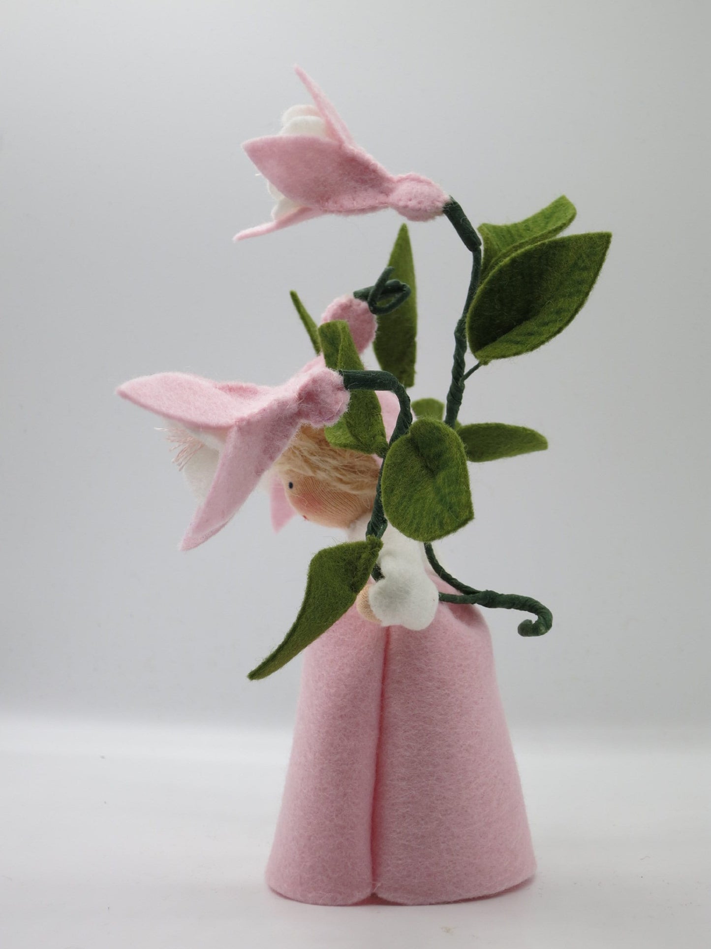 Rückansicht des rosafarbenen handgefertigten Blumenkinds mit Fuchsienzweig