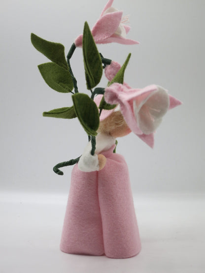 Seitenansicht des rosafarbenen Blumenkinds hinter einem Fuchsienzweig
