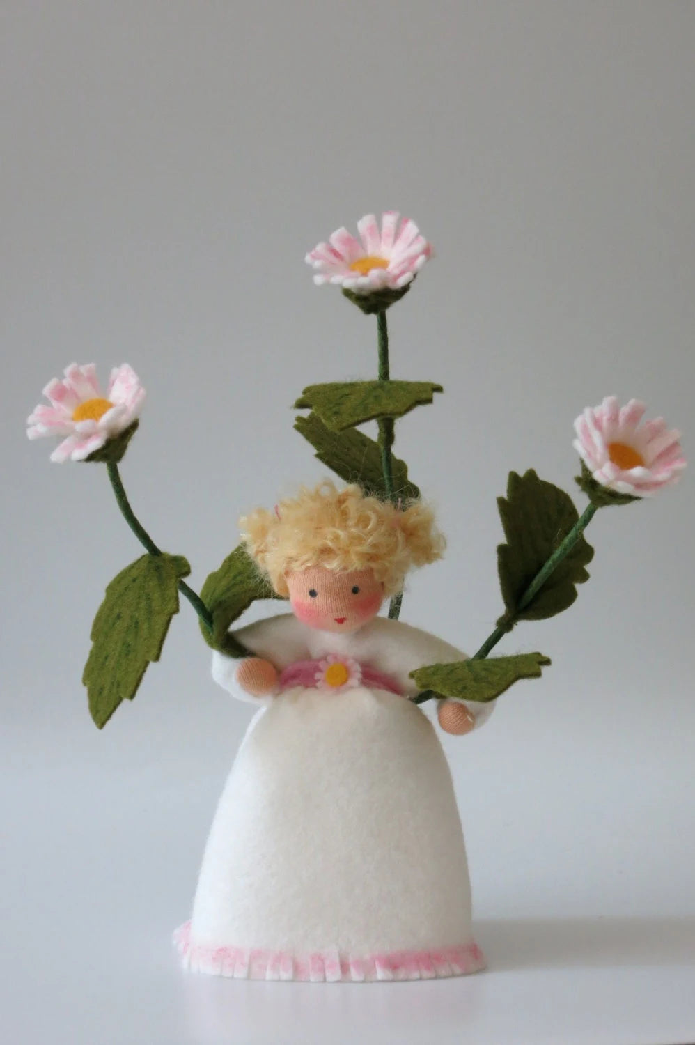 Frontalansicht des Gänseblümchen-Blumenkinds mit blondem Lockenhaar und Blütenschmuck am Gürtel
