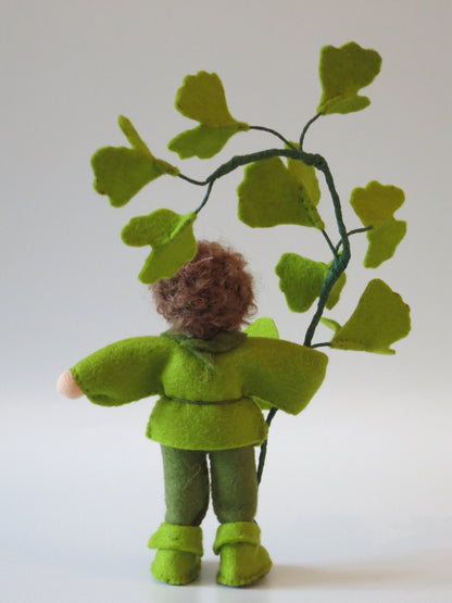 Rückansicht des handgefertigten Ginkgo-Blumenkinds aus Wollfilz mit Ginkgozweig und fächerförmigen Blättern.