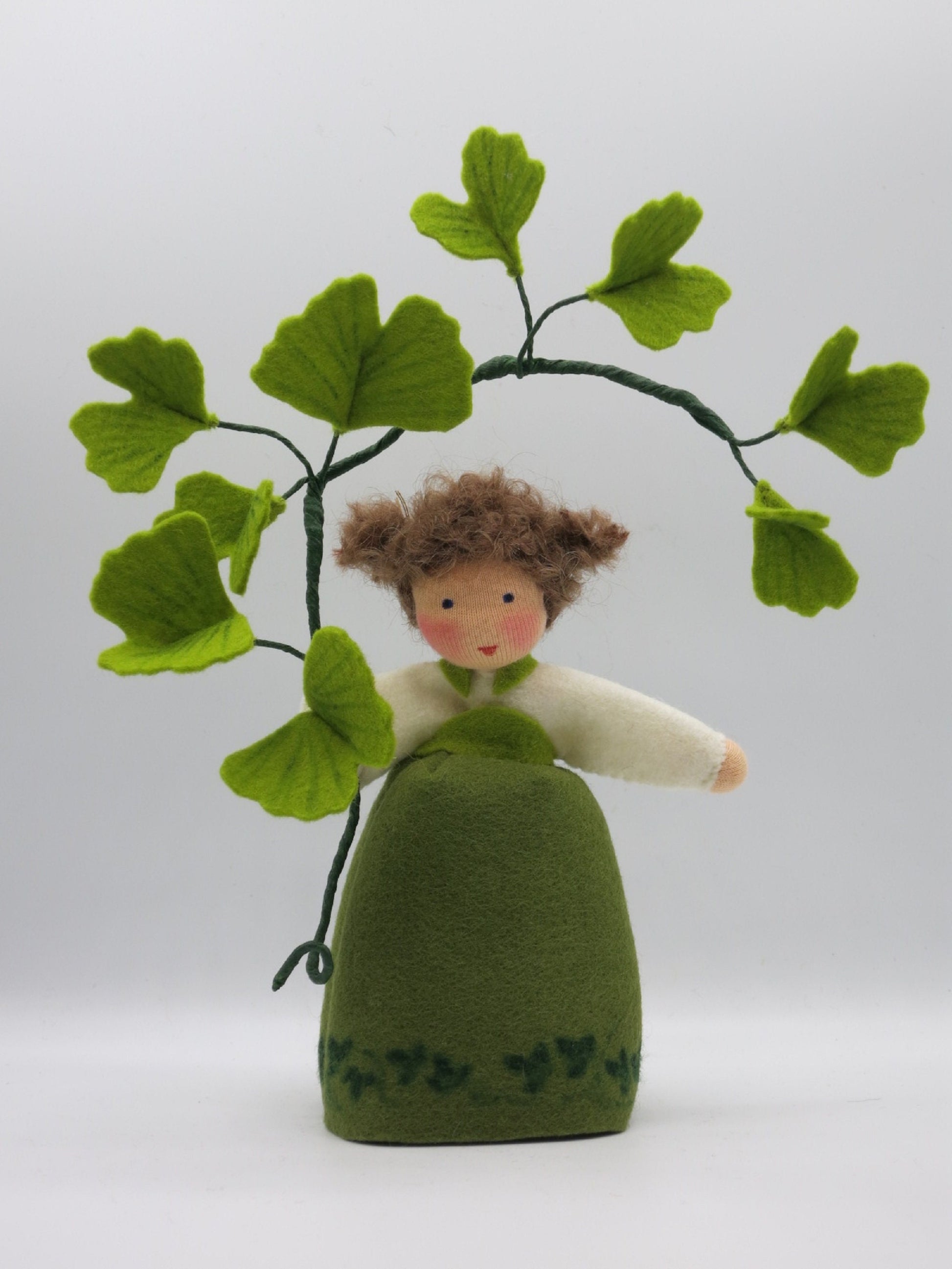 Ginkgo-Mädchen aus Wollfilz mit grüner Kleidung und Ginkgozweig als sommerliche Dekoration für den Jahreszeitentisch.