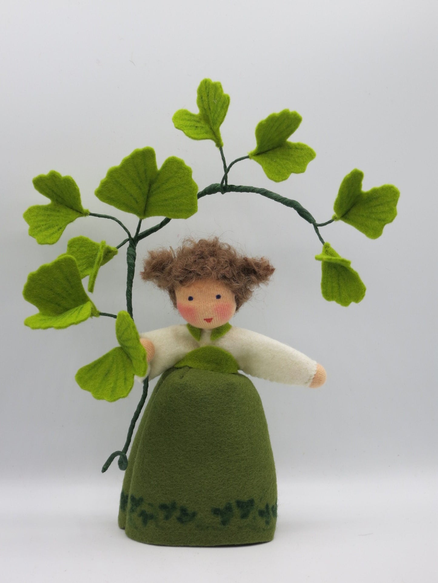 Handgefertigtes Ginkgo-Mädchen aus Wollfilz mit grünem Kleid und Ginkgozweig in Gesamtansicht.