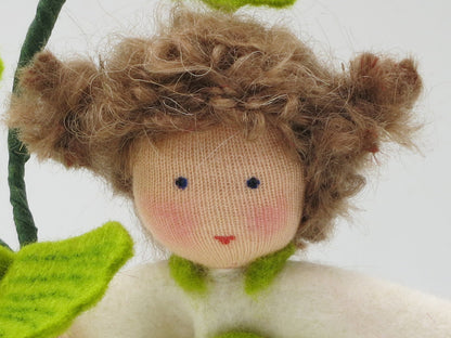 Detailansicht des Ginkgo-Mädchens aus Wollfilz mit rosigem Stoffgesicht und braunem Haar.