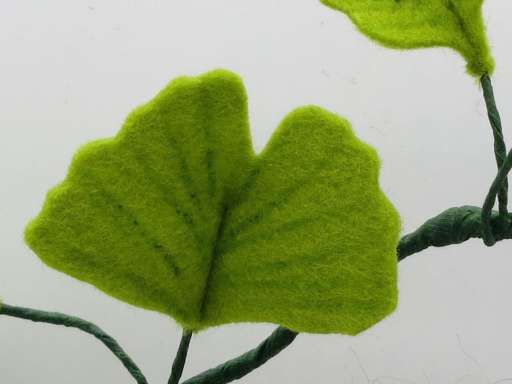 Detailansicht eines fächerförmigen Ginkgoblatts aus Wollfilz am handgefertigten Ginkgo-Mädchen.