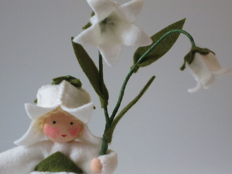 Nahaufnahme der weißen Glockenblüte aus Filz mit grünem Blütenkelch am Blumenkind