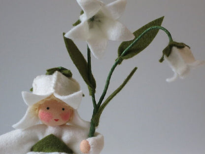 Nahaufnahme der weißen Glockenblüte aus Filz mit grünem Blütenkelch am Blumenkind
