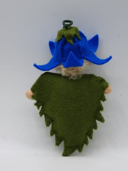 Rückansicht des Glockenblumen-Blätterkinds mit gezacktem grünem Filzkleid und blauem Blütenhut.