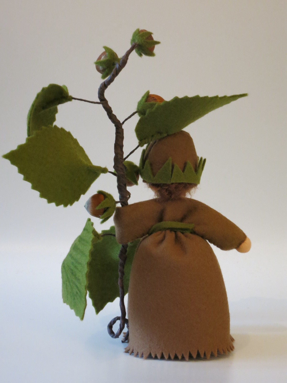 Haselnuss Blumenkind aus Wollfilz, Rueckansicht mit Krone aus gruenem Filz und Haselnusszweig, Waldorf-Jahreszeitentisch, Art. HE38