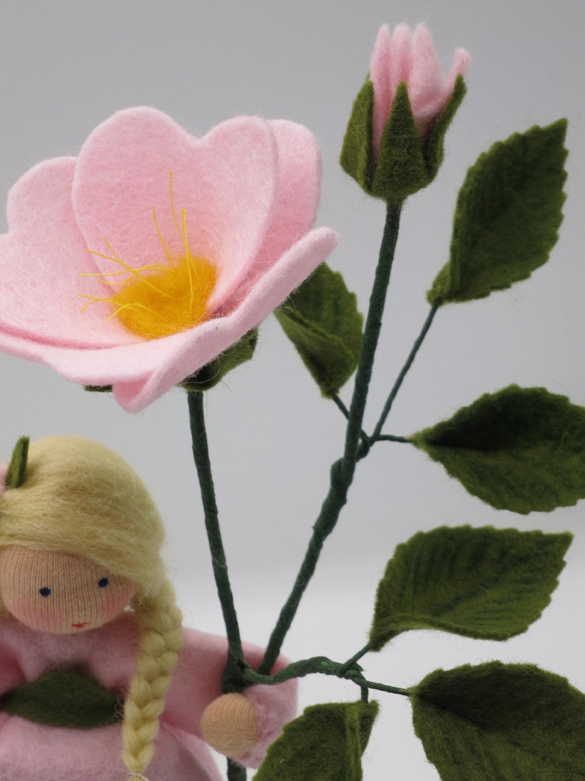 Nahaufnahme der Heckenrosen-Blüte mit Staubgefäßen neben einer zweiten Knospe, Wollfilz-Handarbeit.