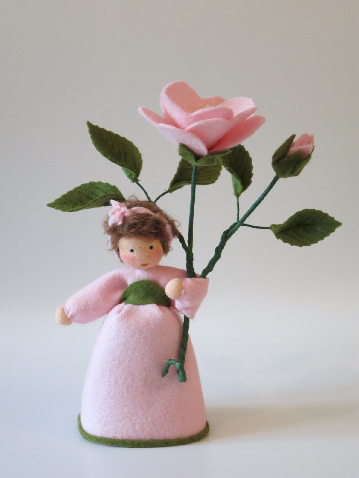 Heckenröschen-Blumenkind aus Wollfilz mit rosa Blüte und Knospe, Frontalansicht.