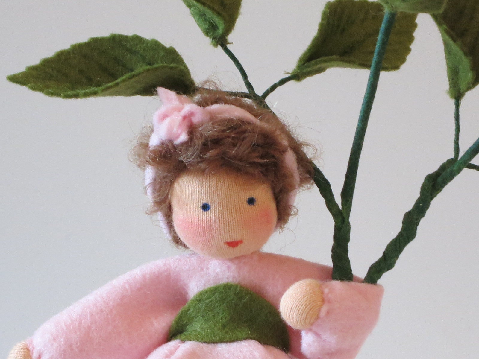 Gesichtsdetail des Heckenröschen-Blumenkinds mit braunem Lockenhaar und rosa Schleife.