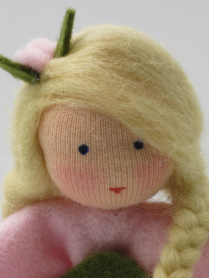 Gesichtsdetail des Heckenröschen-Blumenkinds mit blondem Haar, geflochtenem Zopf und rosa Blütenschmuck im Haar.