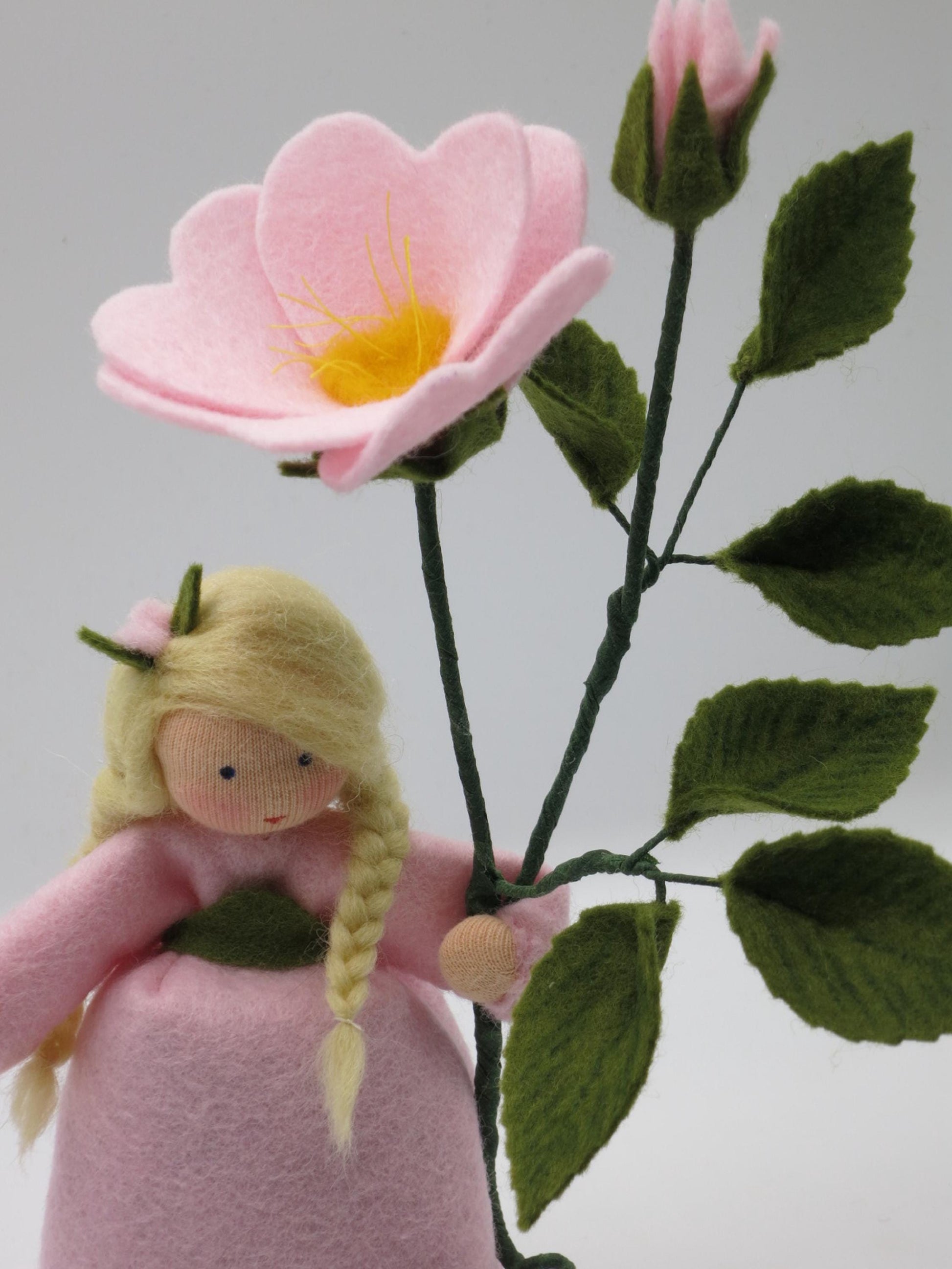 Halbprofil des Heckenröschen-Blumenkinds mit Zopf, Blüte und Knospe am Waldorf-Jahreszeitentisch-Motiv.