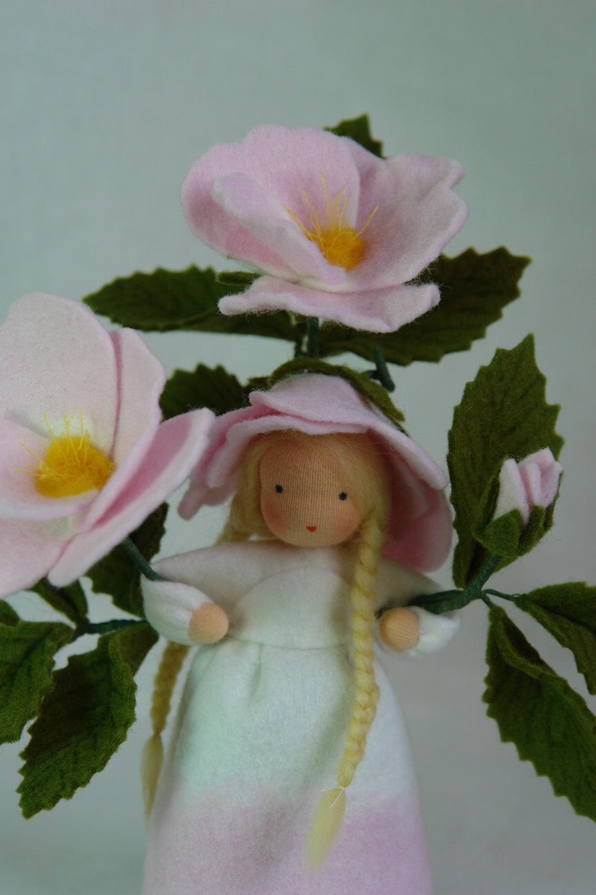 Heckenrose-Figur mit drei Blütenstielen, gesägten dunkelgrünen Blättern und weiß-rosa changierendem Filzkleid.