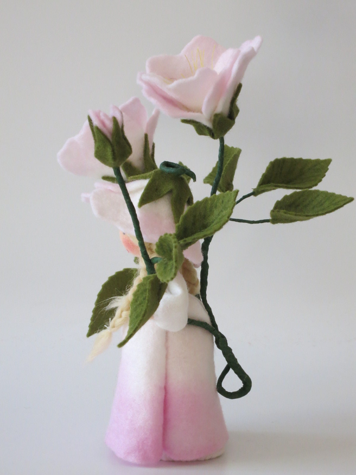 Rückansicht des Heckenrose-Blumenkindes mit eingedrehtem Rankdraht am weiß-rosa Filzkleid.