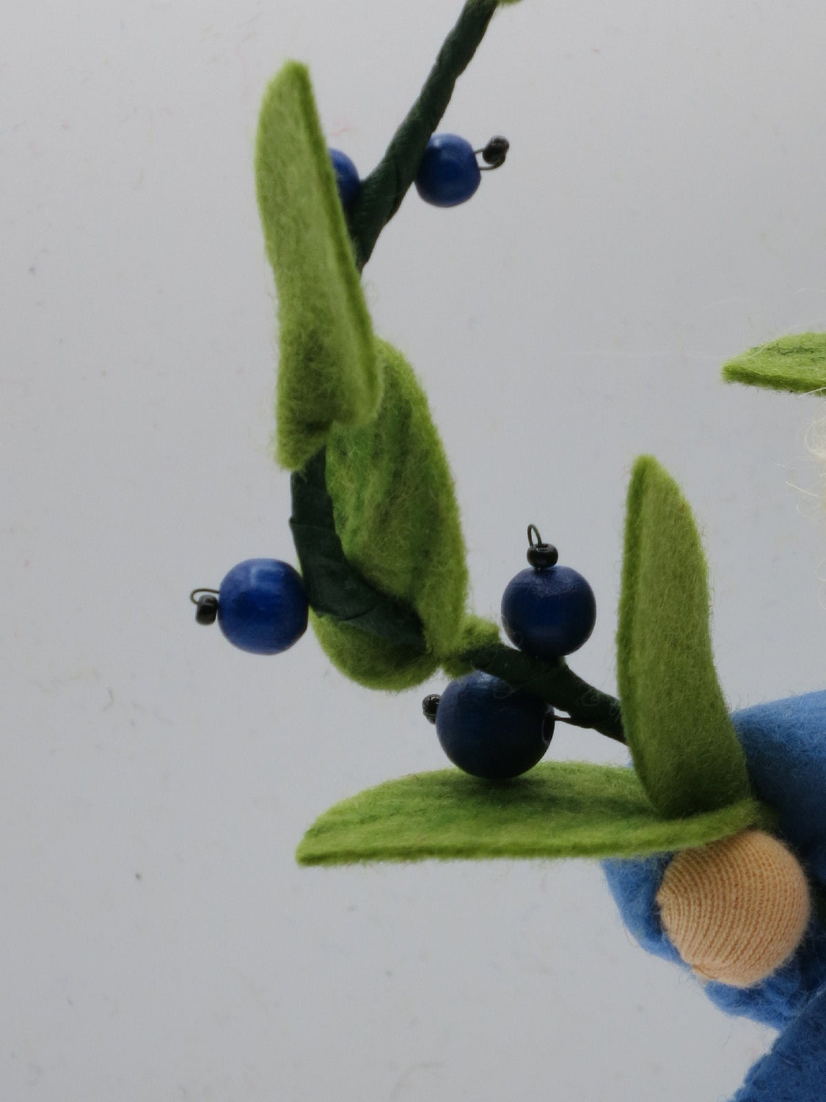 Detailaufnahme der Heidelbeerzweige mit Holzperlen-Beeren am Wollfilz-Blumenkind.
